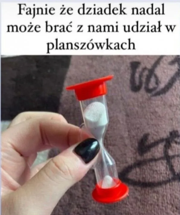 Dłoń trzymająca klepsydrę do gry w kalambury. Napis: "Fajnie że dziadek nadal może brać z nami udział w planszówkach".